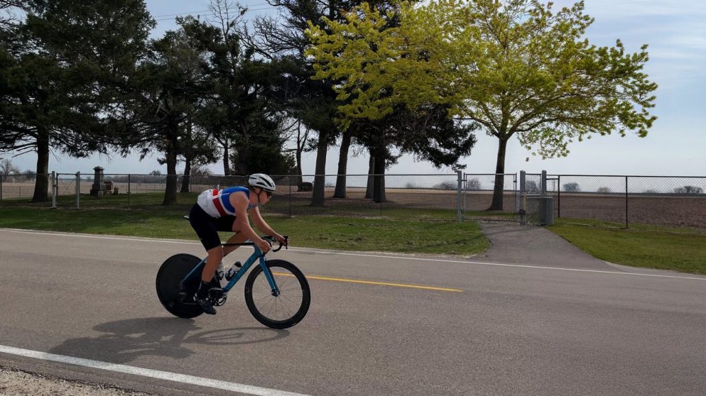 A time trial cyclist races past a cemetery as part of the 10 Mile TT National Championship